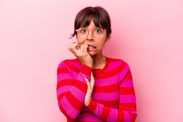 Young hispanic woman isolated on pink background biting fingernails, nervous and very anxious.