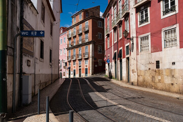 Narrow street in Lisbon Portugal with tram tracks public toilet on the side