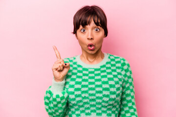 Young hispanic woman isolated on pink background pointing upside with opened mouth.