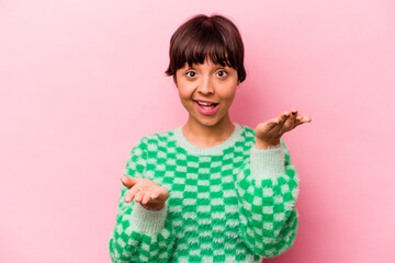 Young hispanic woman isolated on pink background makes scale with arms, feels happy and confident.