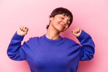 Young hispanic woman isolated on pink background stretching arms, relaxed position.