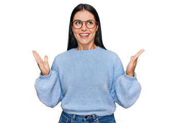 Young hispanic woman wearing casual clothes and glasses celebrating mad and crazy for success with arms raised and closed eyes screaming excited. winner concept
