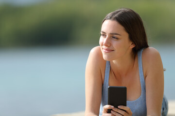 Relaxed woman with phone looking side in a lake