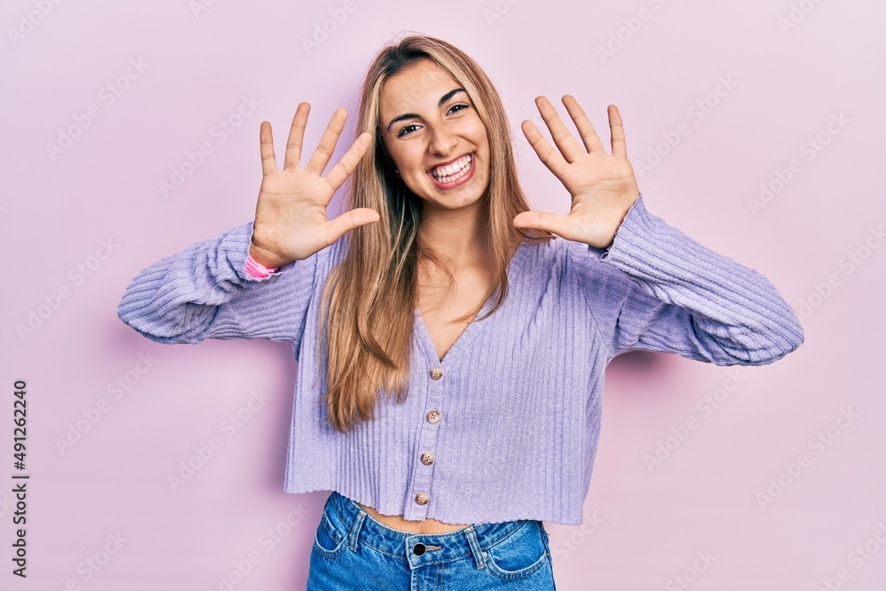 Sticker Beautiful hispanic woman wearing casual shirt showing and pointing up with fingers number ten while smiling confident and happy.