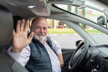 portrait of an elderly driver in car or taxi