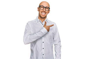 Bald man with beard wearing business shirt and glasses cheerful with a smile of face pointing with hand and finger up to the side with happy and natural expression on face