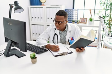 Young african man working as doctor writing notes at medical clinic