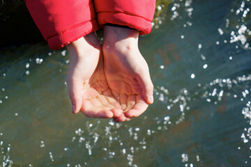 Hands of child with water from river. Water aid, world concept.