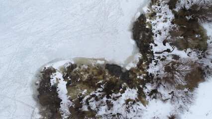 Aerial view of the beginning of the outflow of water from the banks of the river as a result of melting ice and snow in early March