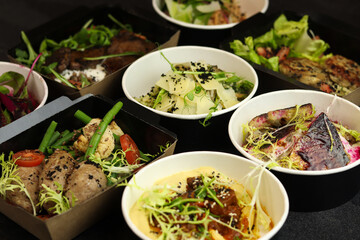 Balanced box diet. Menu suggestions in catering with delivery. Ready healthy food menu in lunch boxes with fish and vegetable packages as daily courier delivery diet plan on black background.
