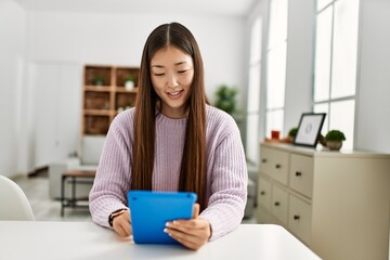 Young chinese girl using touchpad sitting on the table at home.