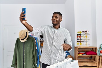 Young african american man holding shopping bag make selfie by the smartphone at clothing store