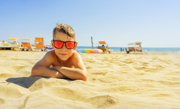 A boy in sunglasses enjoys the sun on the beach. Vacations at the beach.