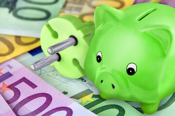 Finanzen und Energie mit grünem Sparschwein, Strom und Euro Geldscheinen