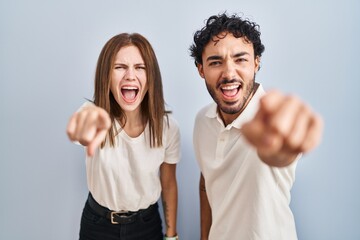 Young couple wearing casual clothes standing together pointing displeased and frustrated to the camera, angry and furious with you