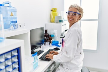 Middle age blonde woman wearing scientist uniform working at laboratory