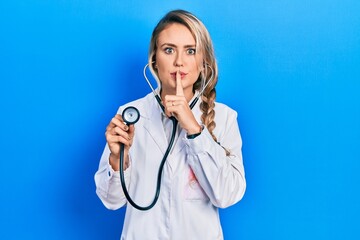 Beautiful young blonde doctor woman holding stethoscope asking to be quiet with finger on lips....