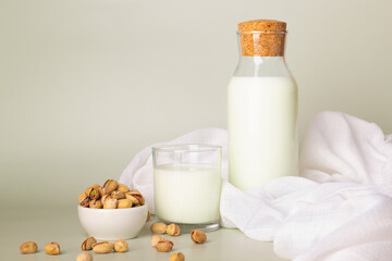Plant-based milk display featuring a bottle and glass of pistachio milk with whole nuts on the side.