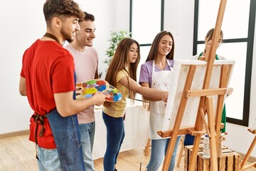 Group of people smiling happy drawing on canvas standing at art studio.