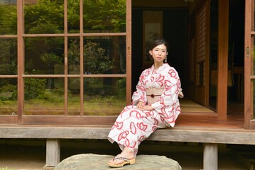 古民家の縁側でくつろぐ浴衣を着た笑顔の若い女性