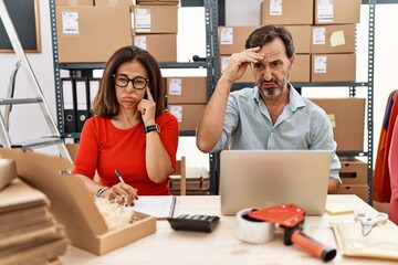 Middle age couple working at small business ecommerce worried and stressed about a problem with...