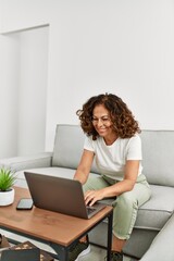 Middle age hispanic woman smiling confident using laptop at home