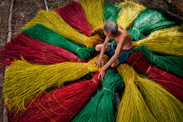 Vietnamese old man craftsman drying traditional vietnam mats in the old traditional village at dinh...