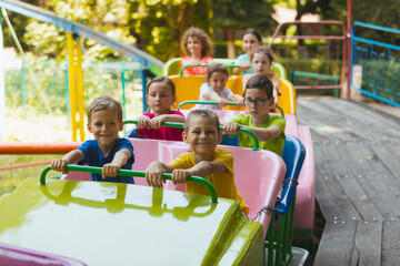 Fototapeta na wymiar The happy kids on a roller coaster in the amusement park
