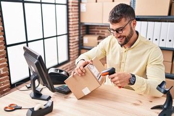 Young hispanic man ecommerce business worker scanning label using barcode reader at office