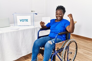 Young african woman sitting on wheelchair voting putting envelop in ballot box strong person...