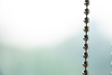 Close up a metal chain of a roller blind with blurred background for copy space.