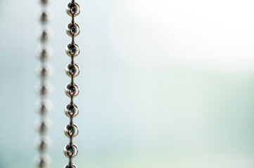 Close up a metal chain of a roller blind with blurred background for copy space.