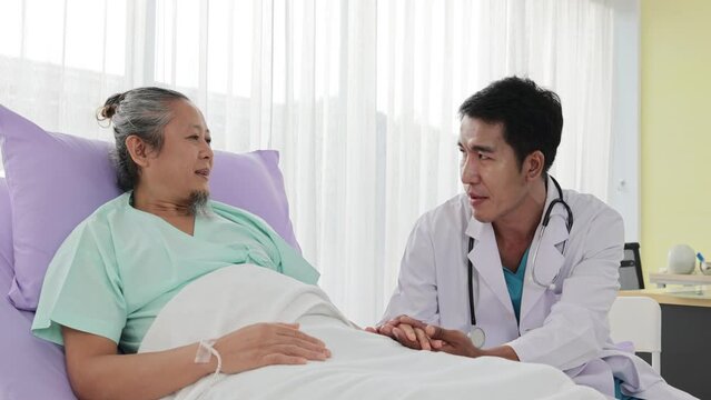 Asian male doctor shakes hands of elderly patient and talks to good news Feels good in hospital bed