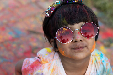 Colorful Holi Theme - Portrait Of Cute Indian Kid Wearing Round Colored Shades And Painted In Holi Color Powder Called Rang Gulal Abeer Or Abir
