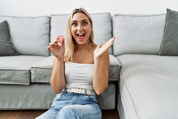Obraz premium Young blonde woman holding menstrual cup celebrating victory with happy smile and winner expression with raised hands