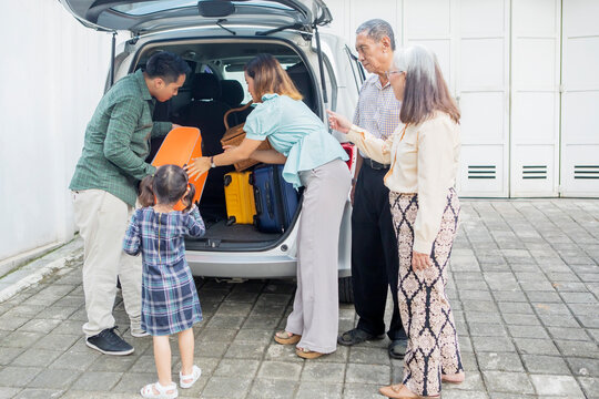 Three Generation Family Prepare Suitcase Into A Car