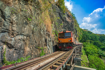 World war II historic railway, known as the Death Railway with a lot of tourists on the train taking photos of beautiful views over Kwai Noi River.