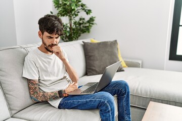 Hispanic man with beard sitting on the sofa feeling unwell and coughing as symptom for cold or bronchitis. health care concept.