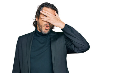 Middle age handsome man wearing business clothes peeking in shock covering face and eyes with hand, looking through fingers with embarrassed expression.