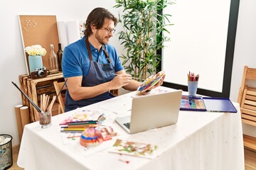 Middle age caucasian man smiling confident having online art class at art studio