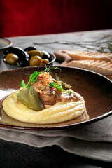 Mashed potatoes with beef stew in sauce, pickles and fried onions. Meat dish served on a plate