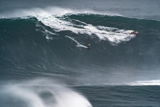 Professional surfer releasing the tow rope that his partner is dragging on the jet ski to surf a giant wave