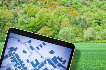 Land plot management - real estate concept with a vacant land on a green field available for building constructionin a residential area for sale - Digital tablet on foreground with an imaginary cadast
