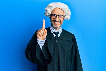 Middle age hispanic man wearing judge uniform smiling with an idea or question pointing finger up...