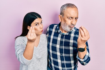 Hispanic father and daughter wearing casual clothes doing italian gesture with hand and fingers confident expression