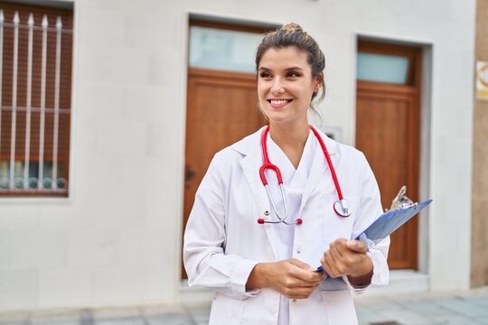 Young blonde woman wearing doctor uniform holding clipboard at street