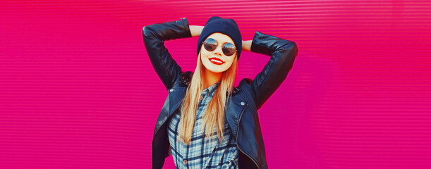 Portrait of stylish blonde young woman in black rock style on vivid background