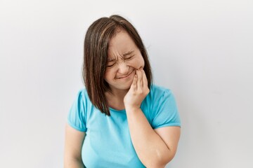 Young down syndrome woman standing over isolated background touching mouth with hand with painful...