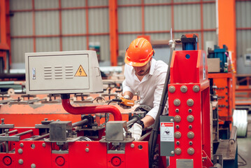Factory worker checking electrical machine process at industrial worksite , wearing hard hat for safety