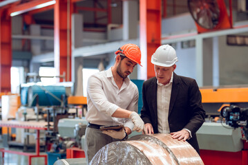 Factory worker foreman and engineer manager working together at industrial worksite , wearing hard...
